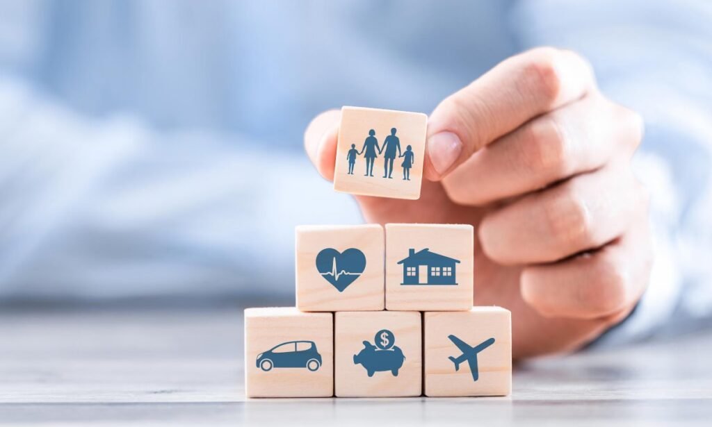 Mano apilando cubos con íconos de familia, salud y casa: el seguro de vida y los herederos